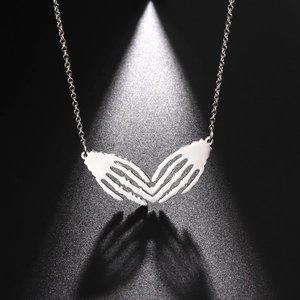 Macro detail of gothic skull hand heart pendant with polished metal finish on black back