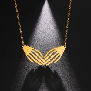 Detailed view of gothic golden necklace featuring skull hands forming a heart shape pendant