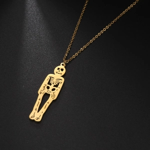 Vue détaillée d'un pendentif squelette en acier inoxydable doré sur fond noir mat