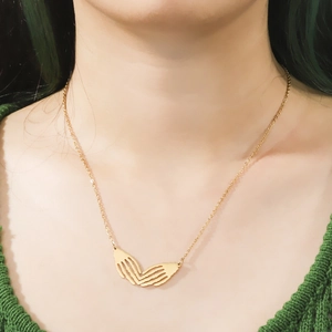 Gothic gold skull hand heart pendant necklace worn on a person for Halloween cosplay