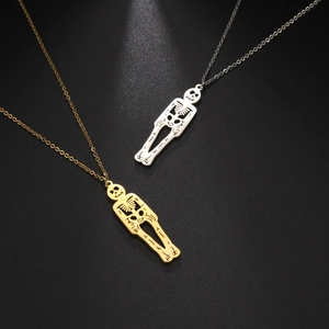 Détail de pendentifs squelettes gothiques en finition or et argent sur fond mat