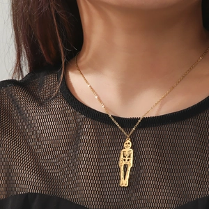 Gros plan détaillé d'un collier pendentif squelette doré porté sur un haut en résille noir