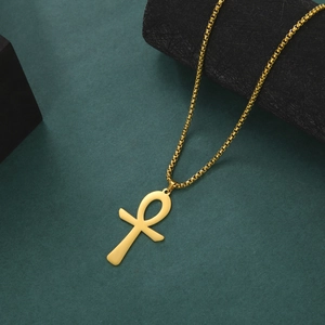 Makroaufnahme des goldenen Anch-Kreuz-Anhängers an einer Rundboxkette vor grünem Grund