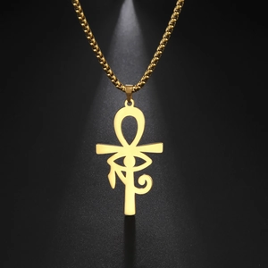 Détail du pendentif Ankh doré en acier inoxydable avec l'Œil d'Horus sous un projecteur