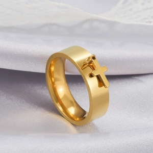 Detailed macro view of a polished gold wide ring featuring a dangling solid cross charm