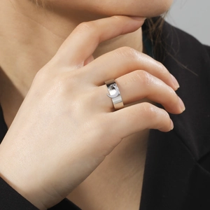 Polished stainless steel ring with crescent moon pendant on person wearing black blazer