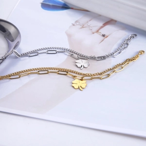 Detail of 18K gold titanium double-layered chain bracelets with clover pendants