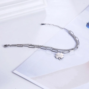Close-up of double-layer stainless steel bracelet with four-leaf clover pendant and lobster clasp
