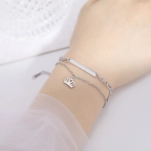 Double-layer stainless steel bracelet featuring crown charm and rectangular tag pendant