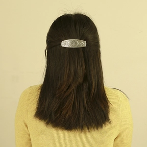 Detailed view of vintage silver Viking rune hair clip on model's dark brown hair