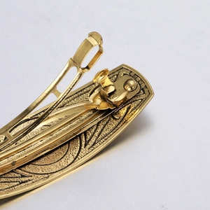 Vintage gold metal hair clip featuring embossed scroll patterns and spring buckle detail