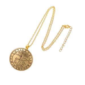 Detalle del colgante de talismán dorado con símbolos místicos y cadena de cordón encerado