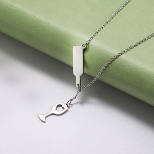 Detalle del collar con colgante de botella de vino y copa de corazón en plata pulida