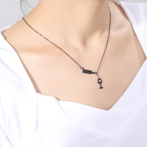 Primer plano de collar negro con colgante de copa de vino en modelo con prenda de color blanco