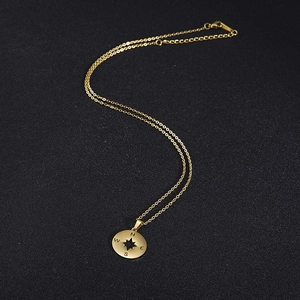 Detail van gouden kompas hanger met ster uitsparing en gegraveerde NESW letters