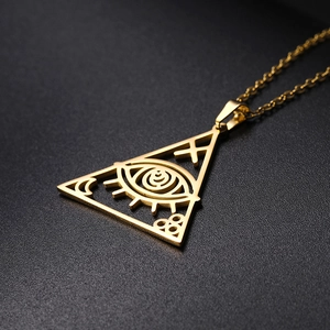 Λεπτομέρεια χρυσού τριγωνικού μενταγιόν με χάραξη ματιού σε μαύρο ανάγλυφο φόντο