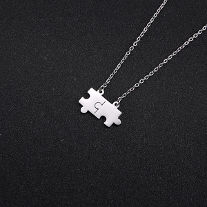 Dettaglio dei ciondoli a forma di puzzle a incastro in argento su una catena sottile