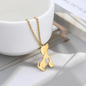 Macro shot of minimalist hollow dog pendant on a delicate gold chain hanging on a white cup