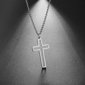 Macro shot of silver hollow cross pendant with polished steel chain on dark background