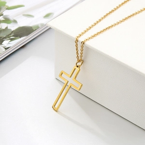 Detailed close-up of a hollow gold cross pendant on an O-chain over a white display box