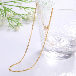 Classic 18k gold plated water wave chain necklace draped on a glass for daily wear