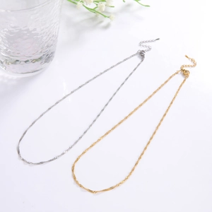 Detail of adjustable gold and silver water wave chains with lobster clasps on a white base