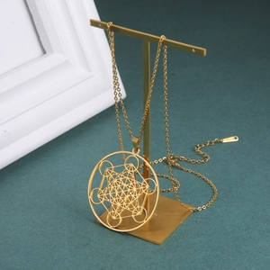 Détail du pendentif cube de Métatron sur une chaîne dorée posée sur un support à bijoux
