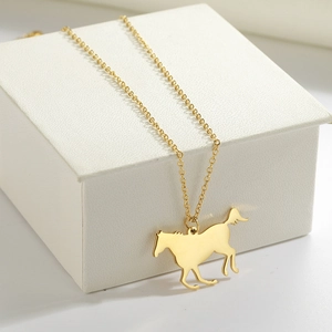 Detail of a gold horse pendant on an O-chain resting inside a white leather jewelry box