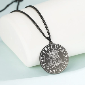 Macro view of black stainless steel Odin pendant with Viking runes and crow engraving