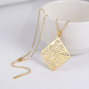 Goldene Halskette aus Edelstahl mit Spinnennetz-Anhänger an weißer Tasse