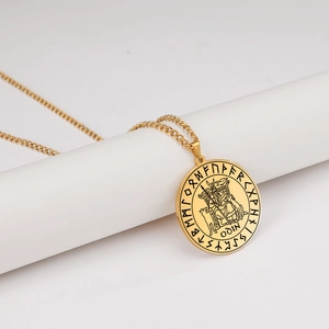 Detailed close-up of golden Viking Odin pendant with Nordic runes on a white pedestal