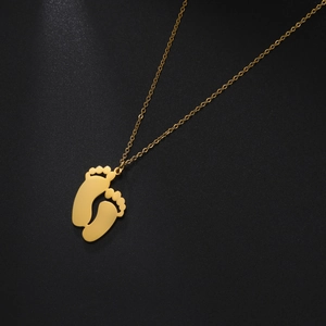 Detailed view of golden double footprint pendant with polished stainless steel chain