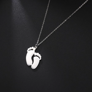 Macro view of polished 304 stainless steel baby footprint pendants on a chain