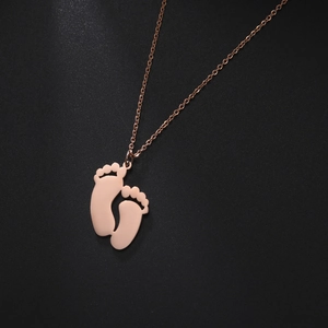 Macro shot of rose gold baby feet pendant on a polished stainless steel chain
