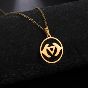 Goldene Edelstahlkette mit geometrischem, hohlem Amulett auf schwarzem Sockel