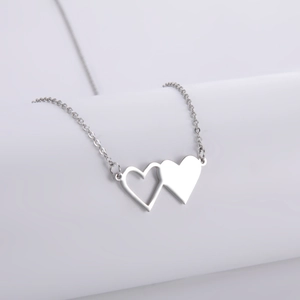 Collana in acciaio inossidabile con doppio cuore intrecciato su espositore grigio
