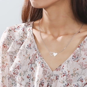 Collana minimalista in acciaio inossidabile con ciondolo a doppio cuore indossata da modella