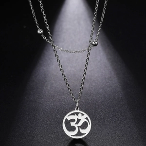 Close-up of double-layered stainless steel necklace with Om symbol pendant on dark background