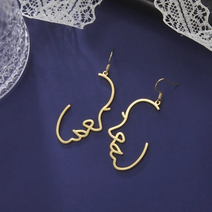 Macro-opname van gouden minimalistische oorbellen met abstract gezicht op blauwe achtergrond