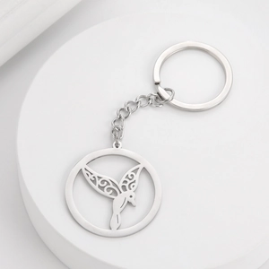 Detailed macro view of a silver stainless steel keychain with an intricate hollow hummingbird pendant