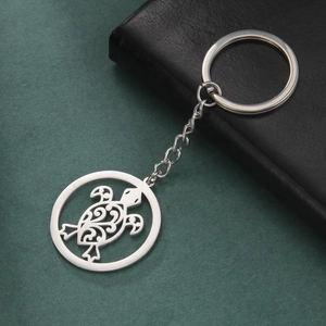 Polished stainless steel keychain with hollow sea turtle pendant on dark textured background