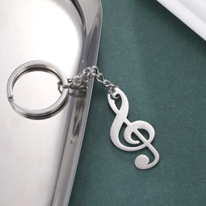 Polished stainless steel treble clef musical note keychain on a dark green background