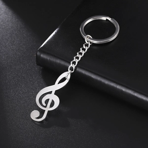 Polished stainless steel treble clef musical note keychain on black leather background