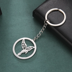 Macro shot of silver hummingbird hollow keychain with floral wings on green background