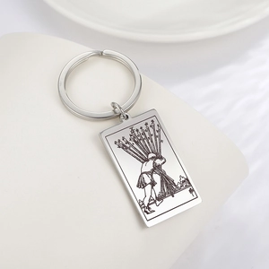 Gros plan de la gravure tarot Dix de Bâtons sur un porte-clés rectangulaire en acier inox