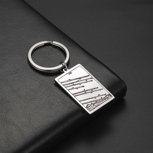 Détail macro du porte-clés tarot Huit de Bâtons sur cuir noir avec finition miroir