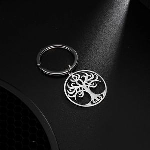 Silver stainless steel tree of life keychain with hollow round pendant on dark surface