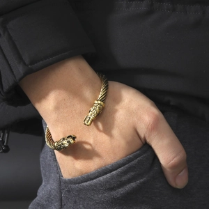 Dettaglio di un bracciale aperto vintage placcato in oro con doppie teste di drago e treccia
