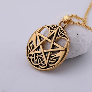 Macro shot of vintage bronze pentagram necklace with celtic knot pendant on a stone