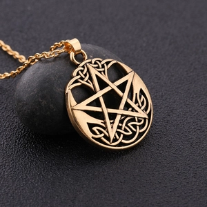 Macro detail of gold pentagram Celtic knot pendant on grey stone with O-chain